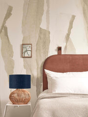Tischleuchte Kalahari von Good&Mojo mit geflochtenem Rattanfuß und blauem Leinenschirm auf einem Beistelltisch.