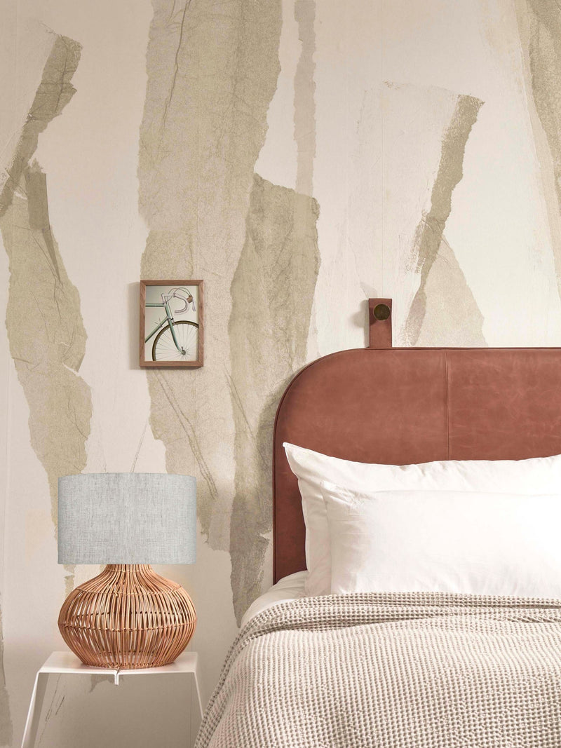 Good&Mojo Tischleuchte Kalahari aus Rattan mit Leinenschirm auf einem weißen Beistelltisch neben einem Bett.