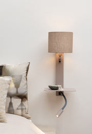Die Wandleuchte Florence mit Leselampe von RoMi: sandfarbener Leinenschirm, flexible Leselampe und Ablageboard über einem Bett.
