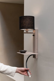Wandleuchte Florence mit schwarzem Leinenschirm, sandfarbenem Eisengestell und flexibler Leselampe vor heller Wand.