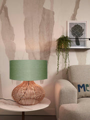 Good&Mojo Tischleuchte Kalahari mit Rattanfuß und grünem Leinenschirm auf einem Marmorbeistelltisch im Wohnzimmer.
