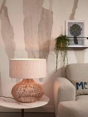Tischleuchte Kalahari von Good&Mojo mit geflochtenem Rattanfuß und hellem Leinenschirm auf Marmortisch im Wohnraum.