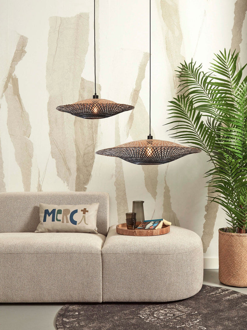 Zwei schwarz-natur geflochtene Bambus-Hängeleuchten Kalimantan von Good&Mojo hängen über einem hellen Sofa in einem Wohnraum.