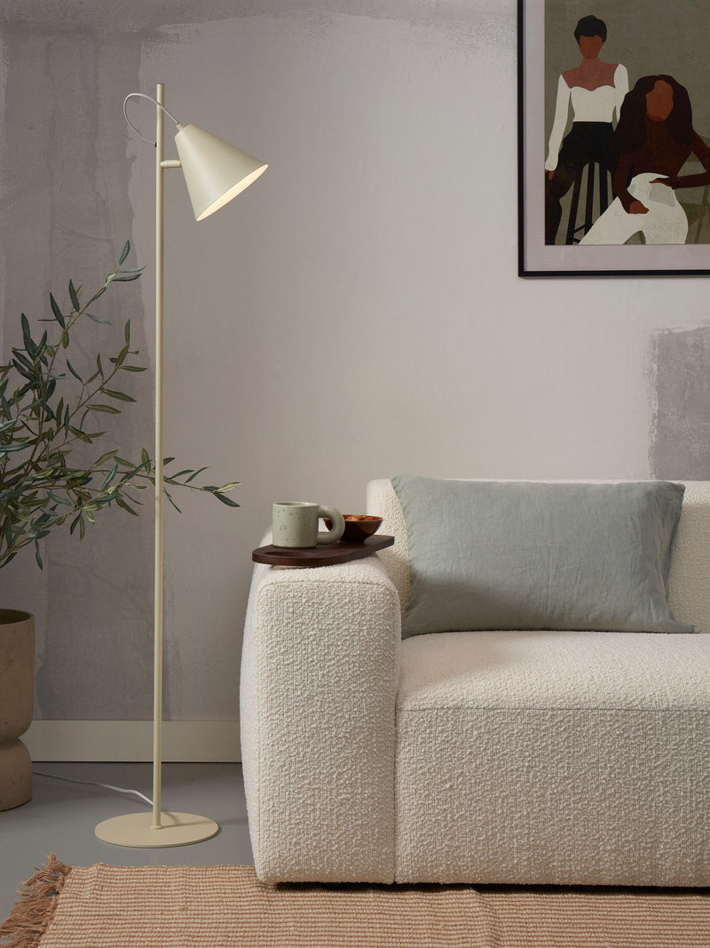 Stehleuchte Lisbon von It's about RoMi mit spitzem Eisenschirm in Beige neben weißem Sofa mit grünem Kissen.