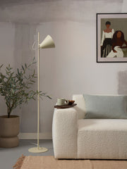 Stehleuchte „It's about RoMi Lisbon“ mit spitzem Schirm in Zartgrün, neben Sofa und Olivenbaum im Wohnraum