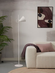 Stehleuchte RoMi Lisbon mit spitzem Eisenschirm in Weiß, daneben ein cremefarbenes Sofa mit rosa Kissen.