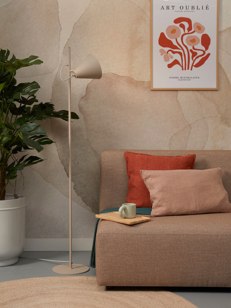 Stehleuchte Lisbon von It's about RoMi in Sand mit spitzem Eisenschirm, neben Sofa und Monstera im Wohnraum.