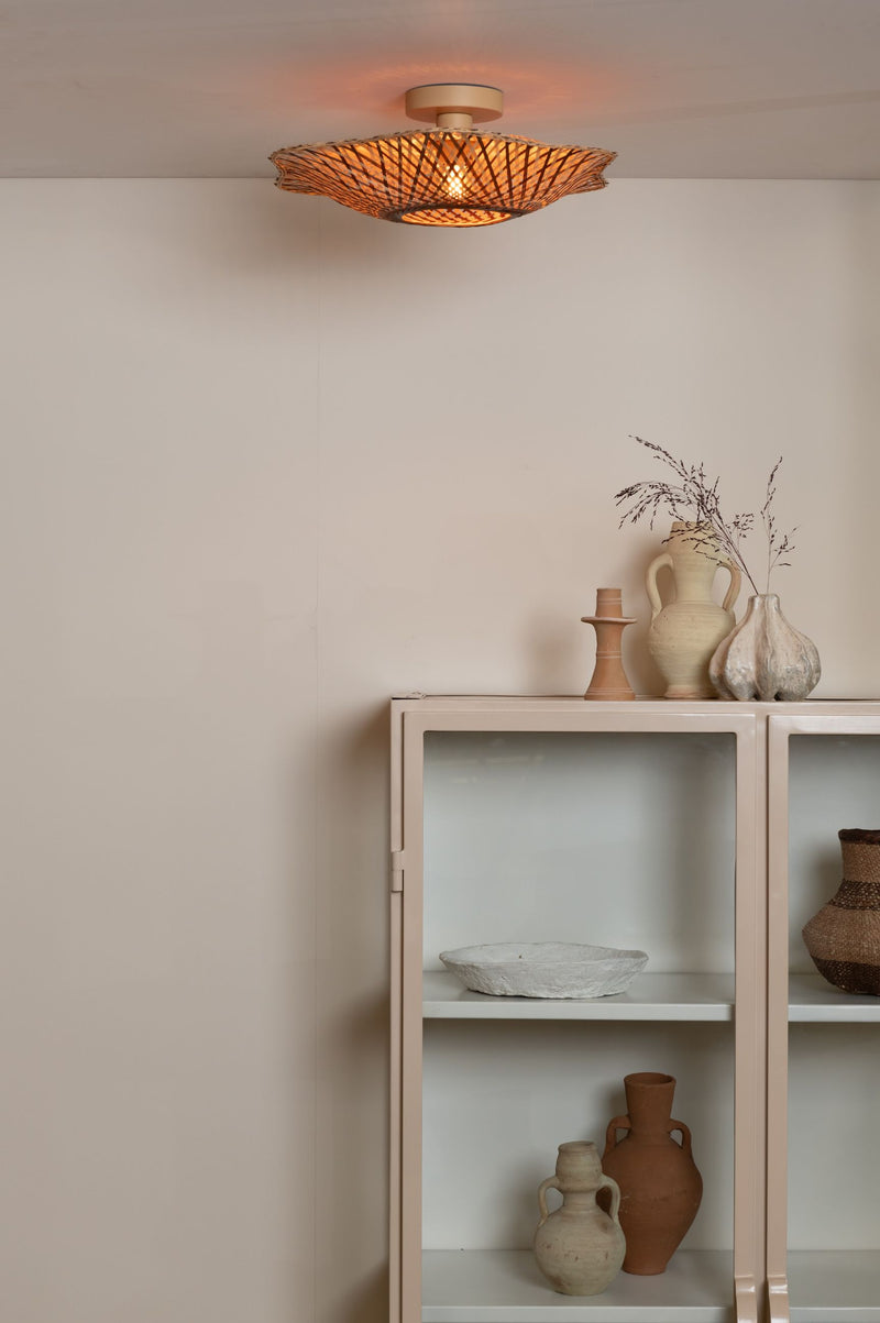 Deckenleuchte Madura aus Bambus in Erdtönen, eingeschaltet über einem beigen Sideboard mit Keramikvasen.