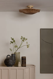 Deckenleuchte Madura von Good&Mojo aus geflochtenem Bambus an der Decke, darunter ein Sideboard mit Vasen und Zweigen.