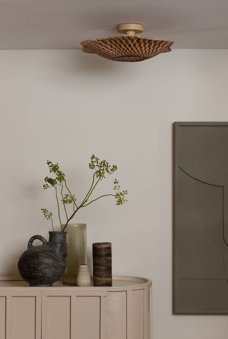 Deckenleuchte Madura von Good&Mojo aus geflochtenem Bambus an der Decke, darunter ein Sideboard mit Vasen und Zweigen.