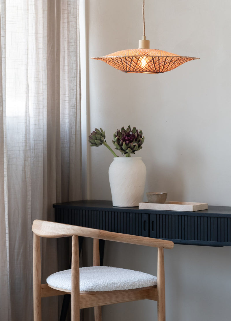 Gesamtansicht: Good&Mojo Hängeleuchte Madura aus Bambus in Erdtönen über einem dunklen Sideboard mit Vase und weißem Stuhl.