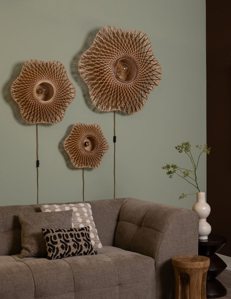 Drei Wandleuchten Madura aus Bambus mit geflochtenem Schirm in Erdtönen hängen über einem Sofa an einer grünen Wand.