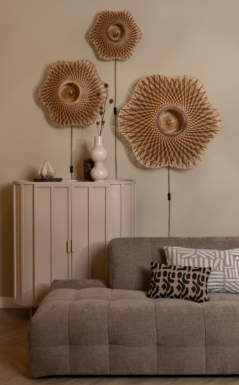 Drei Wandleuchten Madura aus geflochtenem Bambus in Erdtönen hängen über einem beigen Sideboard und einem taupefarbenen Sofa.