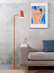Terrakottafarbene Stehleuchte It's about RoMi Marseille mit gebogenem Schirm neben einem grauen Sofa vor Betonwand
