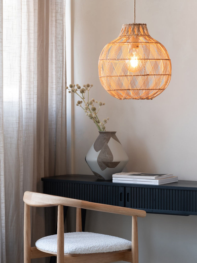 Good&Mojo Hängeleuchte Mendoza aus Bambus mit rundem Schirm, über einem dunklen Sideboard mit Vase und Stuhl, Gesamtansicht