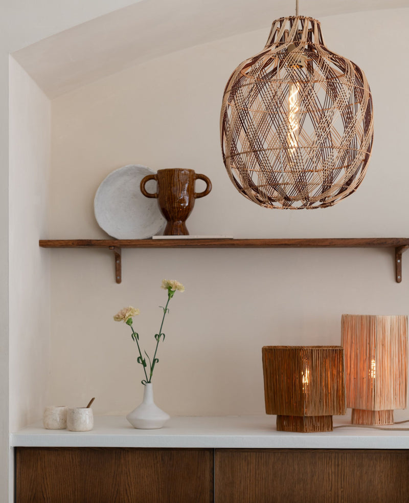 Good&Mojo Hängeleuchte Mendoza aus Bambus mit geflochtenem Schirm über einem Sideboard, daneben Keramikvase und Lampen.
