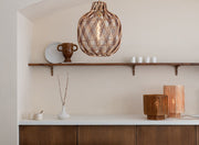 Hängeleuchte Mendoza von Good&Mojo aus geflochtenem Bambus über einem Sideboard mit Keramikvase und Teelichtleuchten.