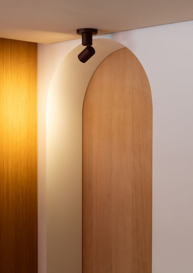 Deckenleuchte RoMi Milan in Bordeaux mit schwenkbarem, zylindrischem Aluminium-Strahler an einer Holz-Putz-Decke.