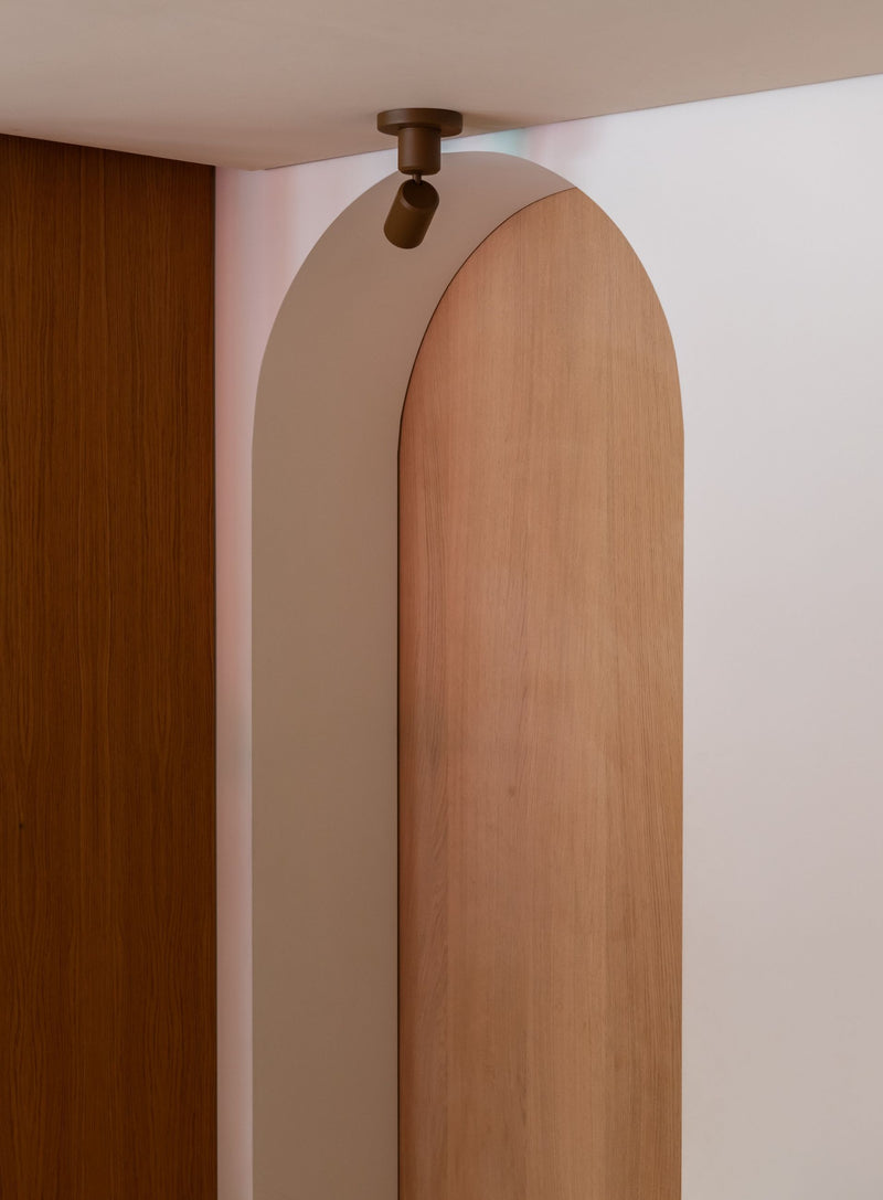 Detailansicht der braunen Deckenleuchte It's about RoMi Milan aus Aluminium mit schlankem Strahler am Holzbogen.