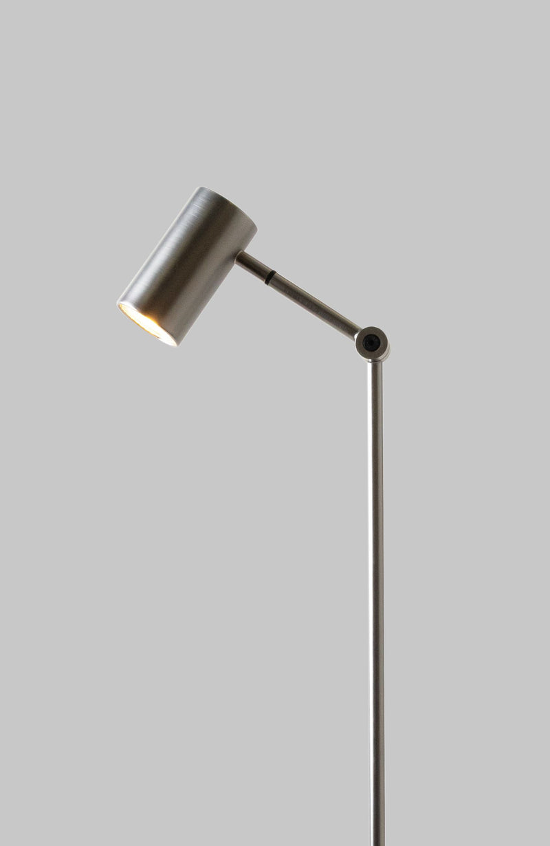 RoMi Stehleuchte Montreux in Nickel: Schlanke Metallstehleuchte mit verstellbarem Strahler vor grauem Hintergrund.