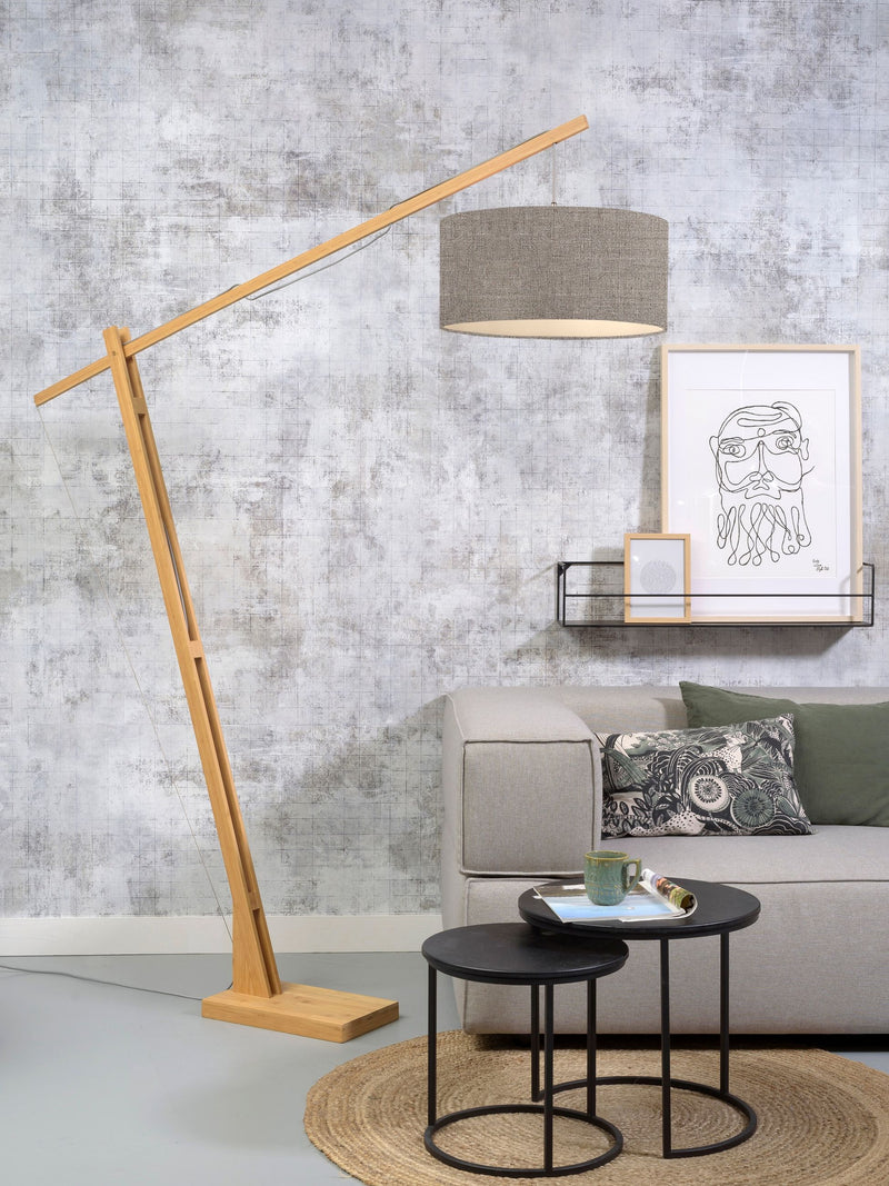 Good&Mojo Stehleuchte Montblanc aus Bambus mit dunklem Leinenschirm, schwenkbarer Bogenarm über grauem Sofa.