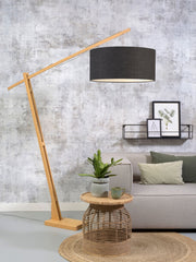 Stehleuchte Montblanc mit dunkelgrauem Leinenschirm und schwenkbarem Bambusgestell vor heller Wand und Sofa.
