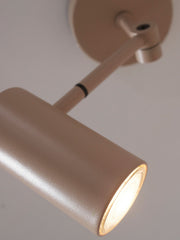 Detailansicht der Wandleuchte It's about RoMi Montreux in Sand: schlanker Metallzylinder mit leuchtender Lichtquelle und verstellbarem Arm.
