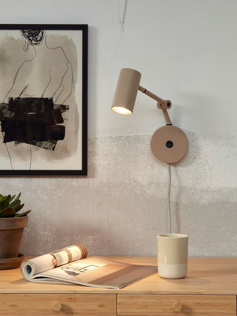 Wandleuchte It's about RoMi Montreux in Sand mit verstellbarem Arm an einer Wand neben einer Holzkommode.