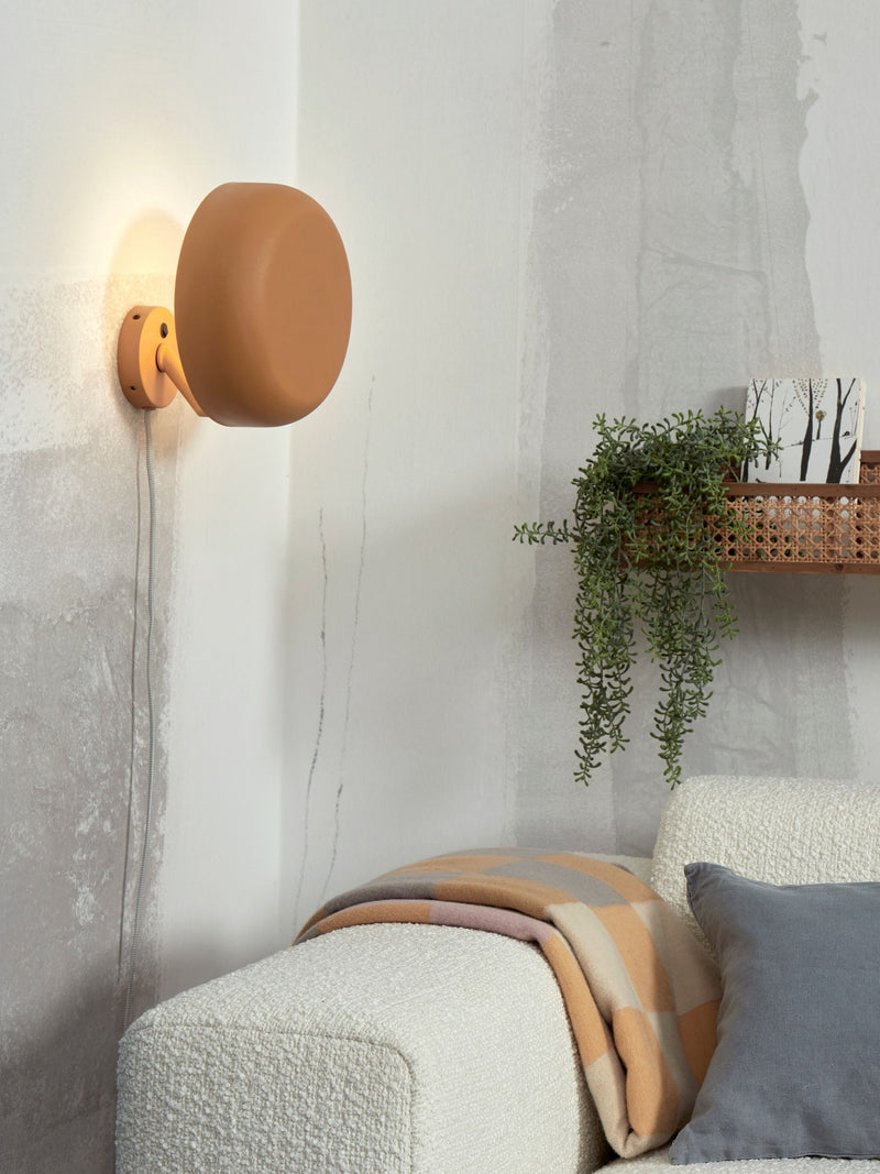 It’s about RoMi Wandleuchte Porto in Senfgelb, aus Eisen, an der Wand über einem weißen Boucle-Sofa montiert.