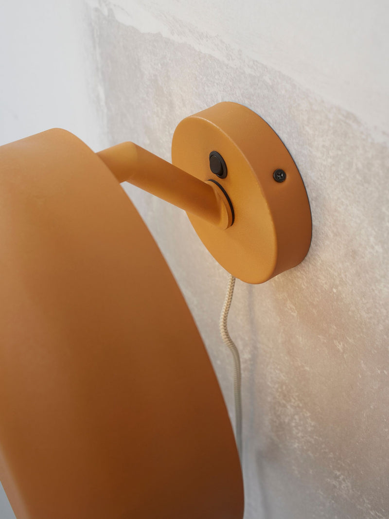 It's about RoMi Wandleuchte Porto in Senfgelb: Detailansicht des Wandgelenks mit Schalter und Kabel vor heller Wand.