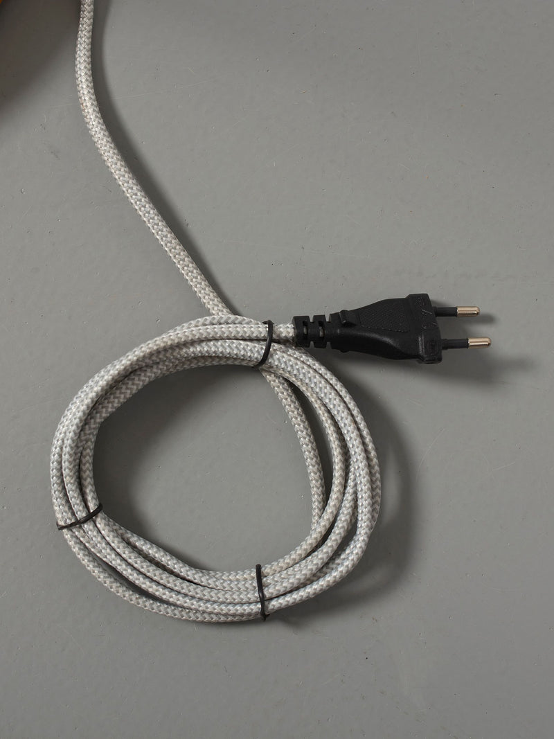 Netzkabel mit grau-weiß gemustertem Textilmantel, zu einer Schlaufe gewickelt, mit schwarzem Eurostecker.