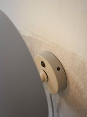 It's about RoMi Wandleuchte Porto in Hellgrau: Detailansicht des runden Metallgehäuses mit Schalter und Kabel an der Wand.