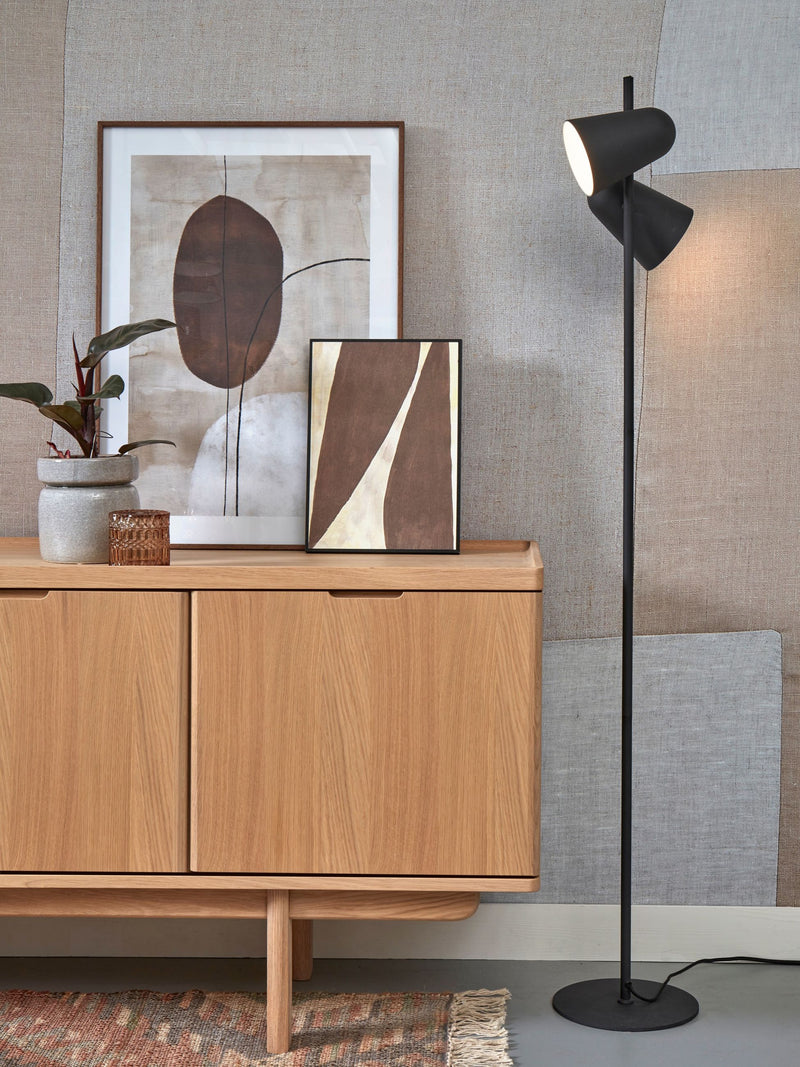 It's about RoMi Stehleuchte Salamanca aus Eisen in Schwarz, mit zwei schwenkbaren Leuchtköpfen neben einem Holzsideboard.