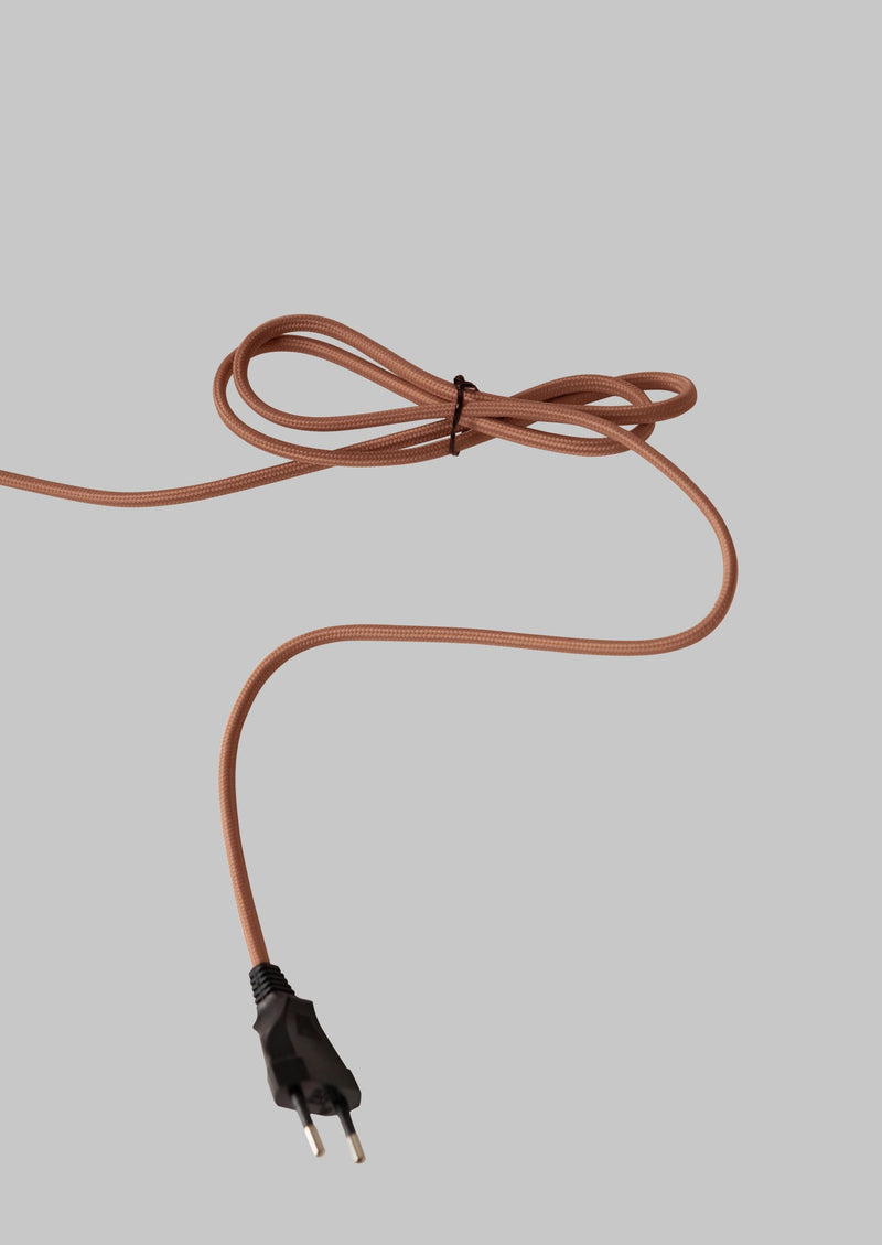 Gewebeummantelte Stromleitung in Terrakotta mit schwarzem Eurostecker und Kabelbinder auf grauem Hintergrund.