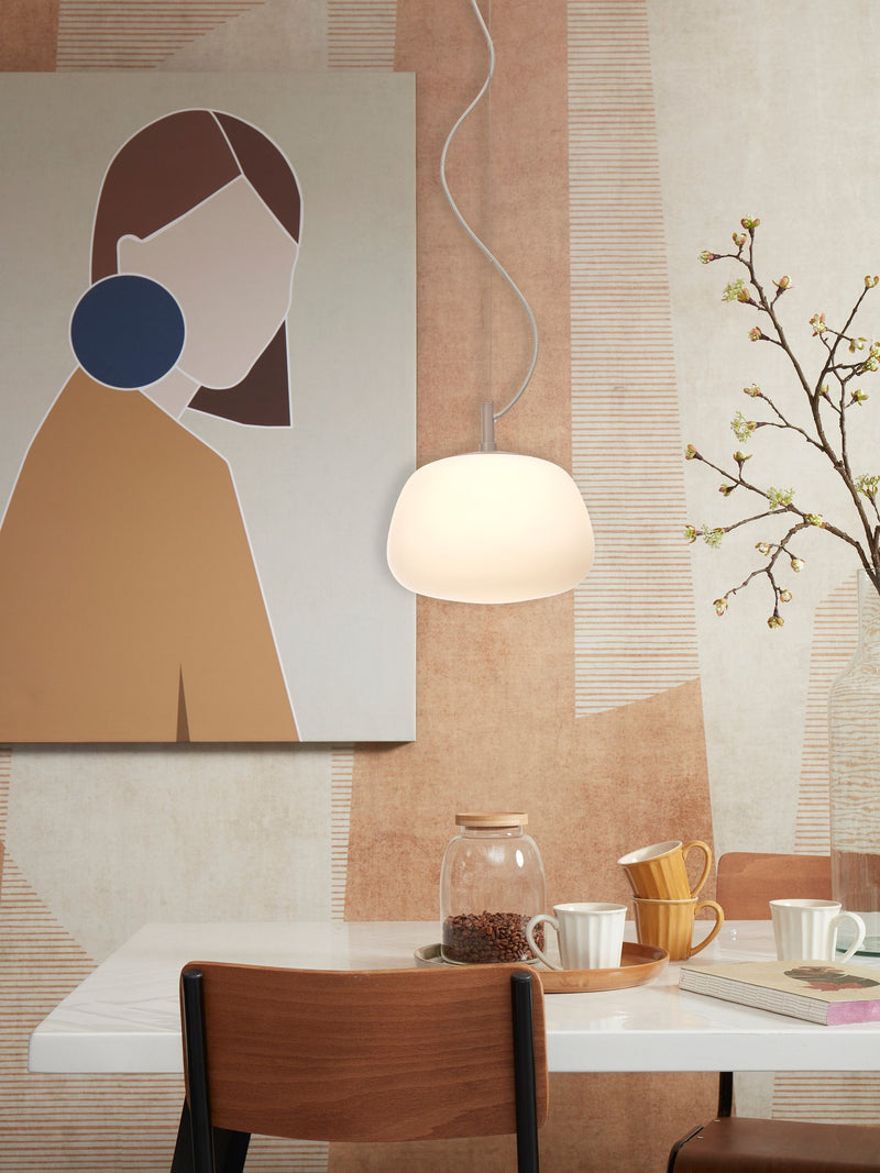It's about RoMi Hängeleuchte Sapporo mit weißem Glasschirm über einem Esstisch mit Kaffeetassen, Glasdose und Blumenzweig.