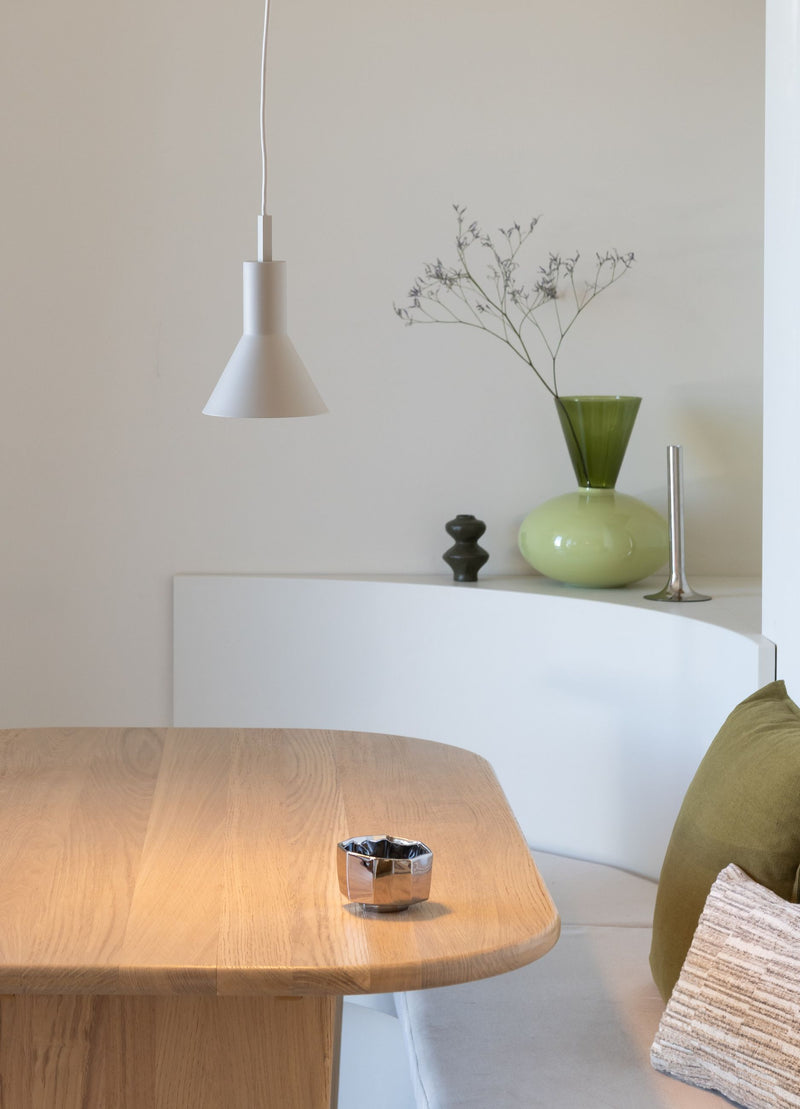 Hängeleuchte Stavanger in Sand von It's about RoMi über einem Holztisch, daneben grüne Vase und Sitzbank.
