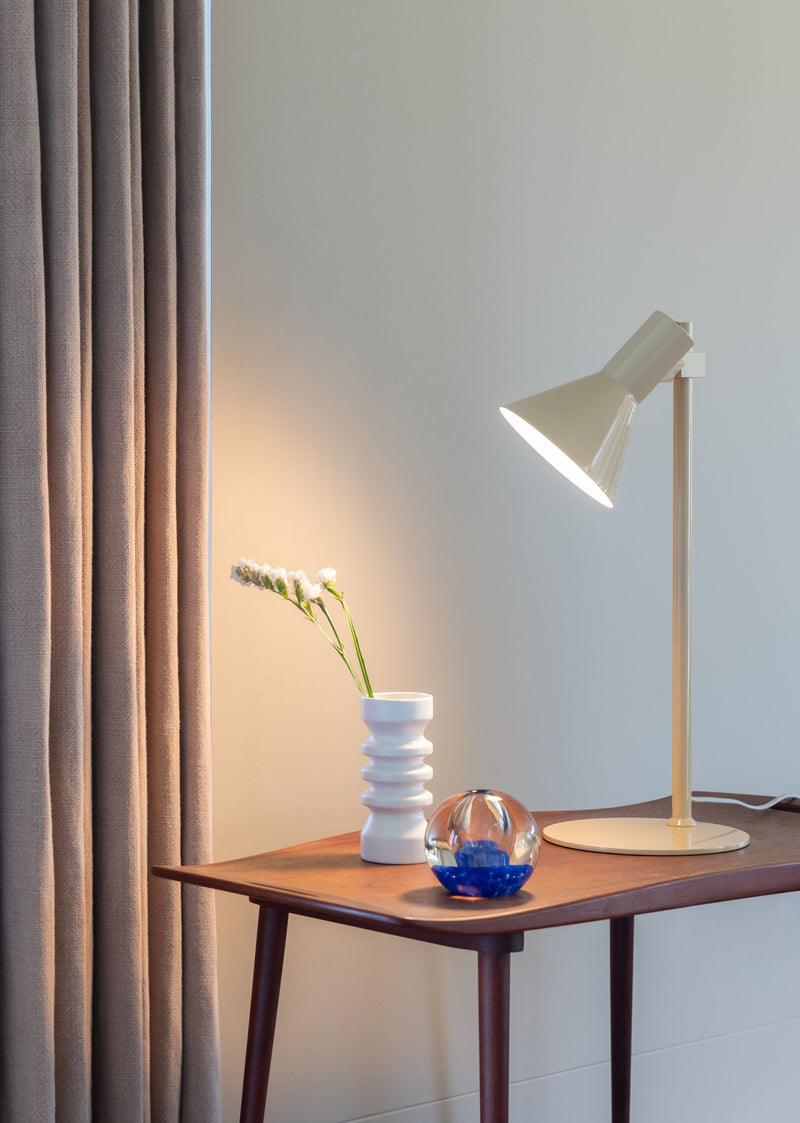 Beige Tischleuchte It's about RoMi Stavanger aus Eisen mit schräg gestelltem Schirm auf einem Holztisch.