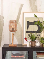 Tischleuchte Tanami von Good&Mojo mit Rattanschirm und Bambusfuß, daneben Sideboard mit Pflanzen und Dekoration.