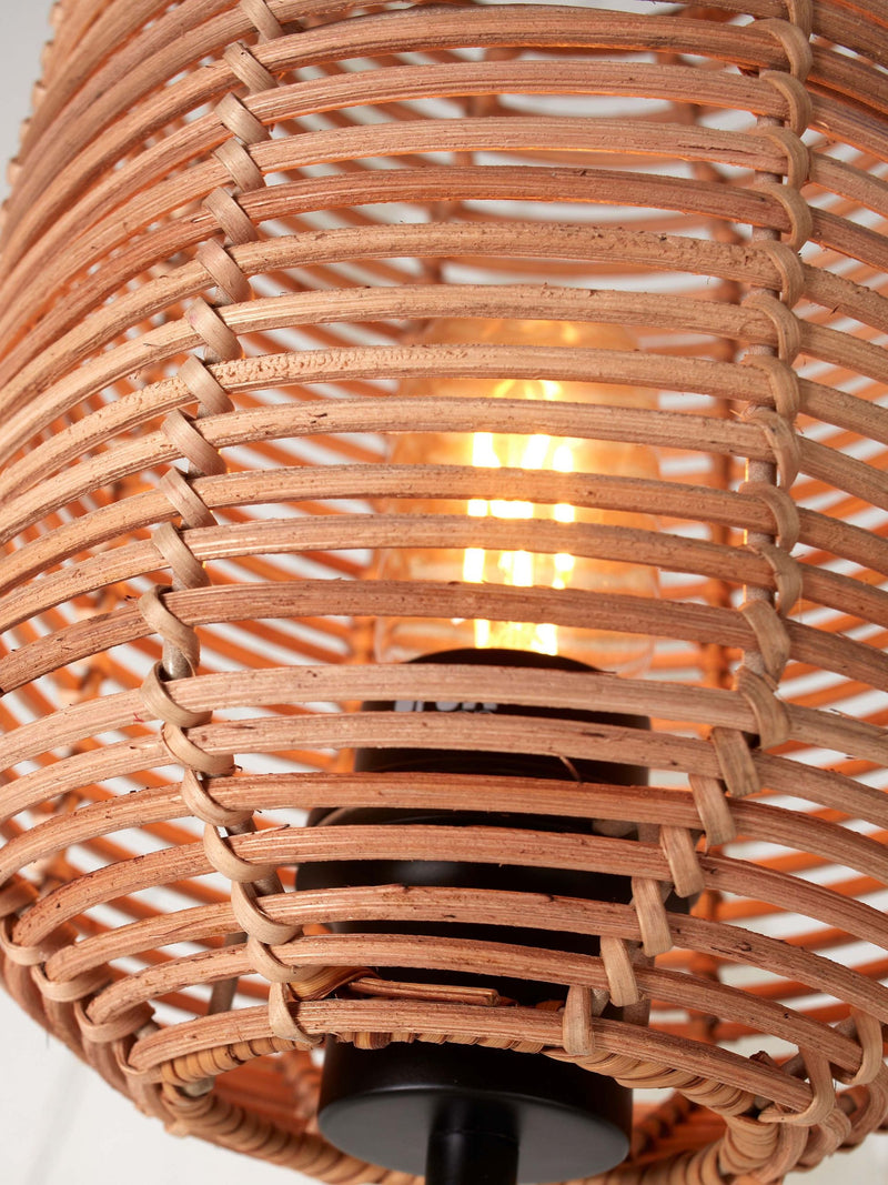 Detailansicht der Tischleuchte Tanami von Good&Mojo mit geflochtenem Rattanschirm in Naturtönen und leuchtender Glühbirne.