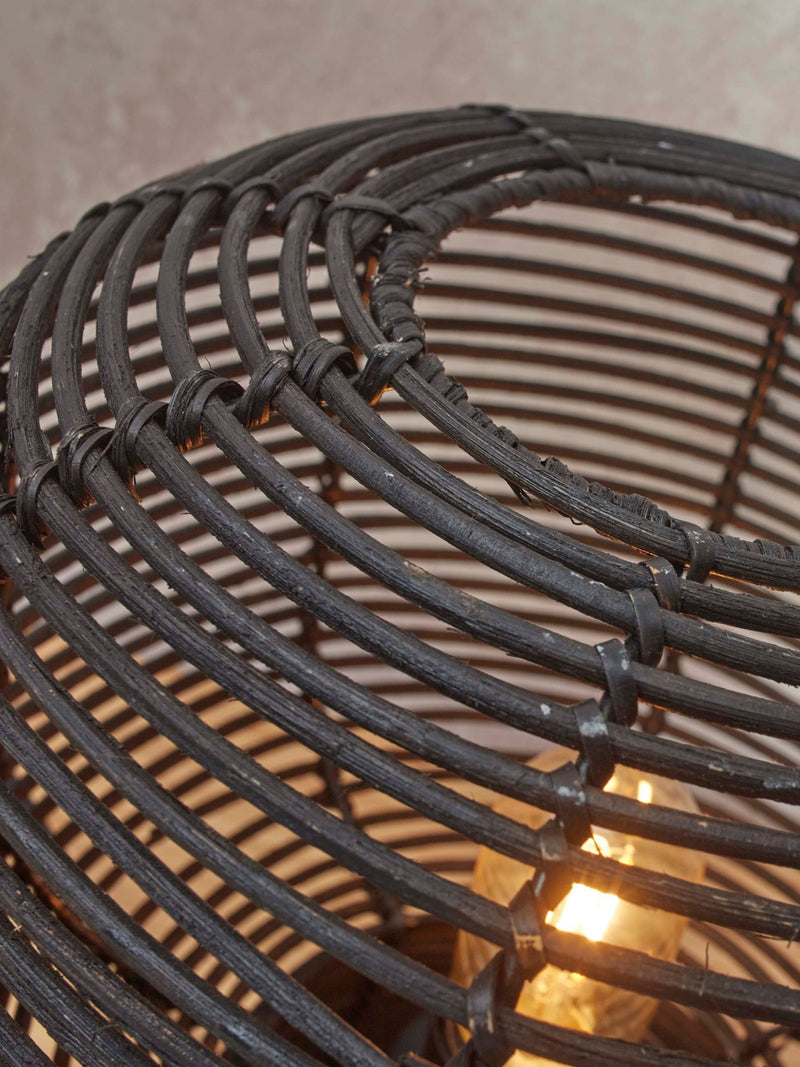 Detailansicht des schwarzen Rattan-Geflechts der Tischleuchte Good&Mojo Tanami mit leuchtender Glühbirne im Inneren.