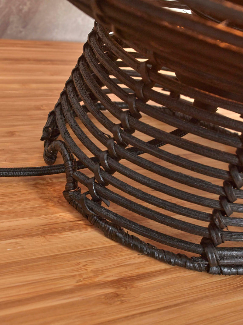 Detailansicht des schwarzen Rattan-Geflechts am Schirm der Tischleuchte Good&Mojo Tanami, auf einer Holzoberfläche.