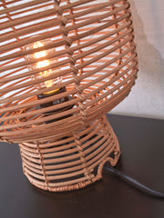 Detailansicht der Good&Mojo Tischleuchte Tanami mit geflochtenem Rattan-Schirm, durchscheinender Glühlampe und schwarzem Textilkabel.