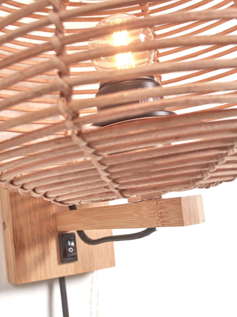 Detailansicht der Good&Mojo Wandleuchte Tanami mit geflochtenem Rattan-Schirm, leuchtender Glühlampe und Bambus-Wandhalterung.