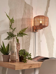 Gesamtansicht der Wandleuchte Tanami von Good&Mojo mit natürlichem Rattanschirm, beleuchtet über einem Holzschreibtisch.