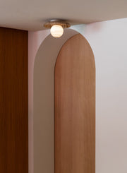 Deckenleuchte RoMi Tivoli in Sand: Travertin-Scheibe mit kugeliger Glasleuchte, montiert an der Decke.