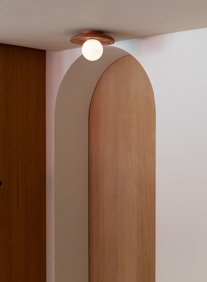 Die RoMi Tivoli Wand- und Deckenleuchte aus Travertin in Terrakotta mit weißem Glasschirm, an einem Bogendurchgang montiert.