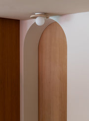 Deckenleuchte It's about RoMi Tivoli mit weißer Glaskugel und Travertin-Scheibe, montiert an einer Decke über einem Bogen.