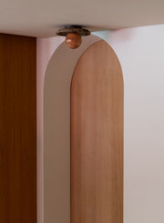 Deckenleuchte „It's about RoMi Tivoli" mit brauner Marmor-Scheibe und kugelförmigem Glasschirm an einer Bogenwand.