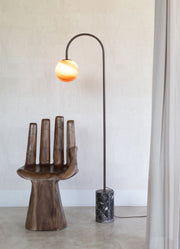 RoMi Stehleuchte Tivoli: Stehleuchte mit kugelförmigem Glasschirm in Orange-Creme, dunklem Metallbogen und schwarzem Marmorfuß.