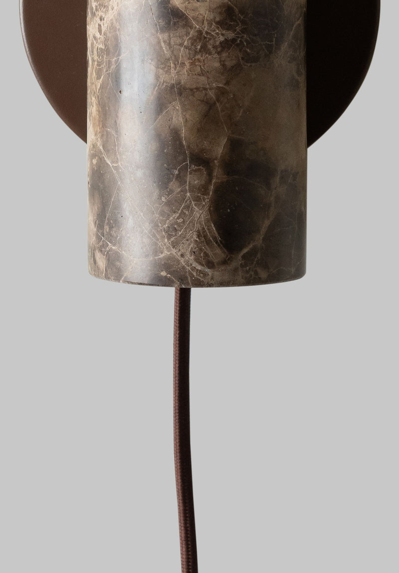 Detailansicht der Wandleuchte Tivoli von RoMi: Zylinder aus braunem Marmor mit dunklen Adern, braunes Stoffkabel.